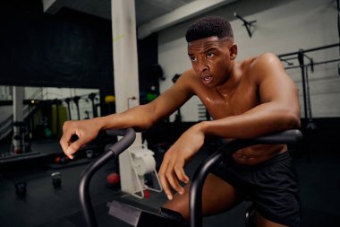 Çapraz antrenman sırasında eliptik antrenör kullanan Afrikalı Amerikalı bir erkek. Erkek kişisel antrenör spor salonunda yoğun bir şekilde egzersiz yapıyor. Yüksek kalite fotoğraf