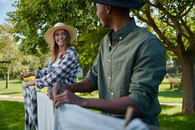 Mixed race male and female farmers hanging out washing on warm summer day. High quality photo