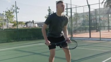 Athletic young biracial man hitting tennis ball with tennis racquet during tennis practice at sports court