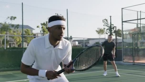 スポーツウェアを身に着けているアスレチック若い男性は スポーツコートでテニス練習中にダブルマッチをプレイ — ストック動画