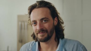 Ofiste kameraya bakarken gülümseyen beyaz gömlekli mutlu genç adamın portresi.