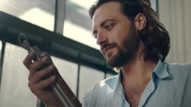 Ofisteki ürünleri incelerken başka tarafa bakan beyaz gömlekli, odaklanmış genç bir adam.