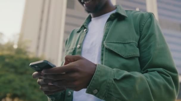 路上で携帯電話を使用してカジュアルな服を着た若い黒人男性のクローズアップ — ストック動画