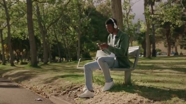 Genç Siyah Adam Gündelik Kıyafetler Giyiyor Cep Telefonu Kulaklık Kullanıyor — Stok video