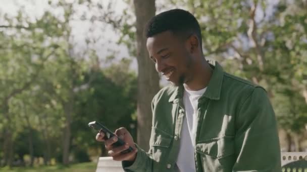 Gelukkig Jonge Zwarte Man Draagt Shirt Met Behulp Van Mobiele — Stockvideo