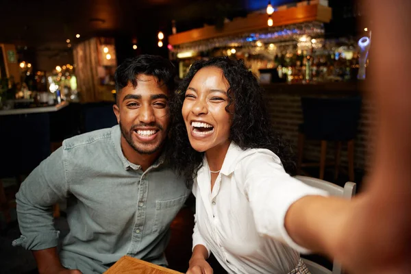 年轻的多种族夫妇穿着休闲装 一边微笑 一边在酒吧用手机自拍 — 图库照片