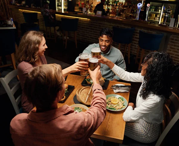 幸せな若い多人種の友人のグループバーで夕食中にビールとトーストを行うカジュアルな服を着て — ストック写真