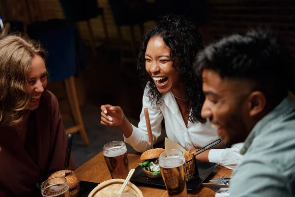 幸せな若い多人種グループの友人のカジュアルな服を着て笑いながら会話の中で夕食 — ストック写真