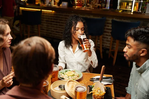 バーで夕食とカジュアルな服を着てビールを飲む友人の若い多人種グループ — ストック写真