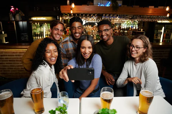 快乐的年轻多种族的朋友们穿着休闲装在餐馆里拿着手机 — 图库照片
