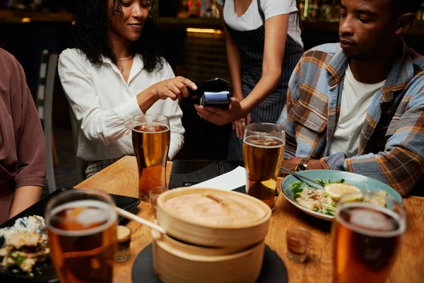 バーで夕食とドリンクを支払うカジュアルな服を着ている友人の若い多人種グループ — ストック写真