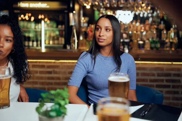 レストランでビールと法案とテーブルに座っている間に離れて見てカジュアルな服を着て若い女性 — ストック写真