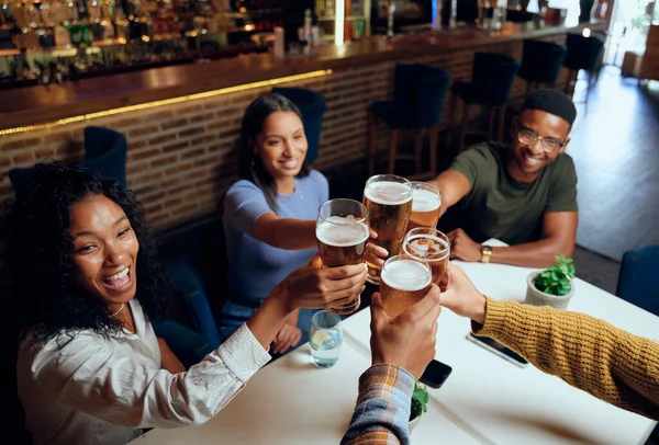 レストランでビールで乾杯するカジュアルな服を着ている友人の幸せな若い多人種グループ — ストック写真