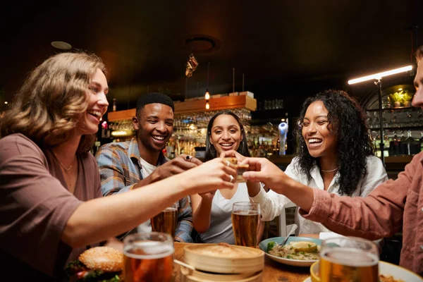 レストランで食事やドリンクを楽しむカジュアルな服を着た友人の幸せな若い多人種グループ — ストック写真