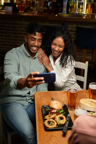 Młoda Wielorasowa Para Uśmiechnięta Podczas Robienia Selfie Telefonem Komórkowym Restauracji — Zdjęcie stockowe