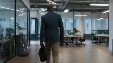 Bir grup çok ırklı iş adamı bir şirket ofisinde bilgisayarlarla etkileşime girip çalışıyor.