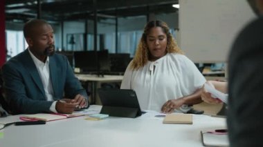 Ofis yönetim kurulu toplantısında turta grafiğiyle konuşan bir grup çok ırklı iş arkadaşı.