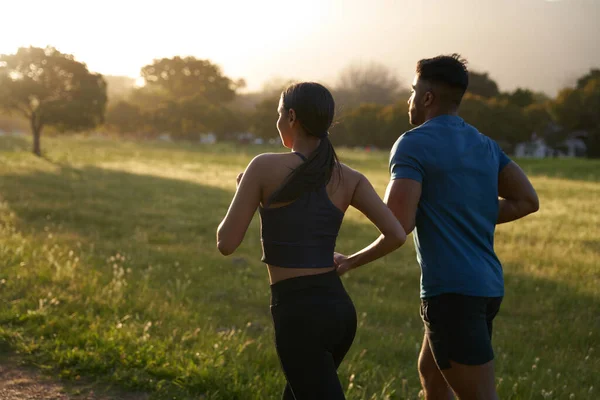 Young multiracial couple wearing sports clothing running side by side in park