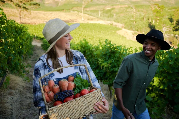 快乐的多种族年轻夫妇 身穿休闲装 面带微笑 面对着农场里的新鲜收获 — 图库照片