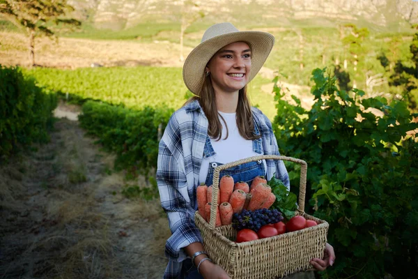 快乐的年轻的高加索女人穿着休闲装 提着篮子里的水果和蔬菜在农场里 — 图库照片