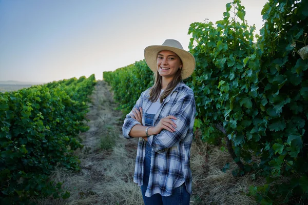 快乐的年轻的高加索女人 身穿格子呢衬衫 胳膊交叉在庄稼之间在农场里 — 图库照片