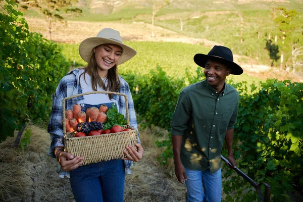 快乐的多种族年轻夫妇穿着休闲装 带着新鲜的收获和叉子在农场里散步 — 图库照片