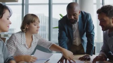 Bir grup çok ırklı meslektaş ofiste iş görüşmeleri ve jestler yapıyorlar.