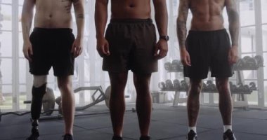 Spor salonunda kollarını üst üste kavuşturmuş üç üstsüz, çok kültürlü genç adam.