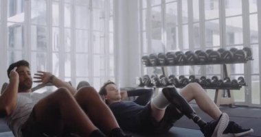 Spor kıyafetleri giymiş iki çok ırklı genç spor salonunda mekik çekiyorlar.