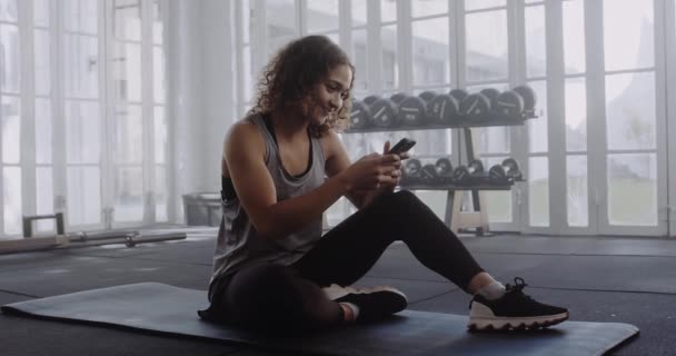 Wanita Multirasial Muda Mengambil Istirahat Dan Mengetik Ponsel Gym — Stok Video