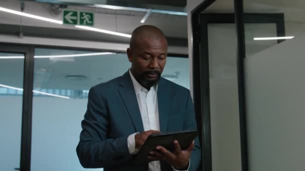 Şirketin Koridorunda Yürürken Dijital Tablet Kullanan Yetişkin Siyahi Bir Adam — Stok video