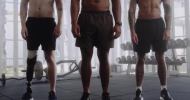 Spor salonunda kolları üst üste bağlı şort giyen üç üstsüz, çok kültürlü genç adam.