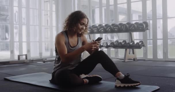Young Multiracial Woman Sportswear Taking Break Typing Mobile Phone Gym — Stock Video