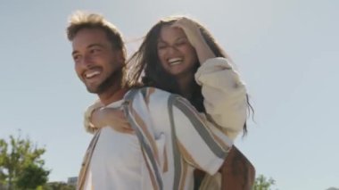 Gündelik giysiler giyen mutlu genç çift kaykay parkında sırtına biniyor.