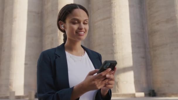 Young Multiracial Woman Wearing Businesswear Using Mobile Phone Headphones Next — Stock Video