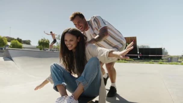 スケートパークでスケートボードで楽しんでいるカジュアルな服を着て幸せな若い多民族カップル — ストック動画