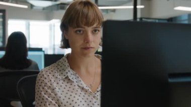 İş hayatında odaklanmış beyaz kadın şirket ofisindeki masada bilgisayar kullanıyor.