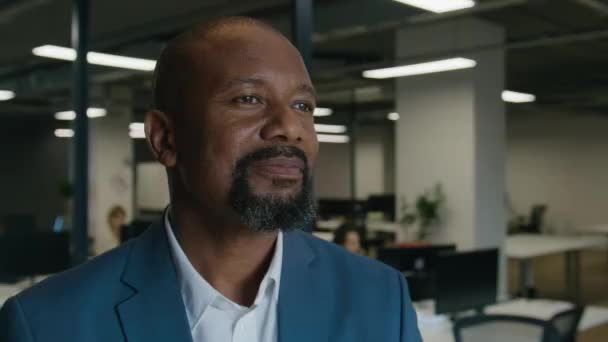 ビジネスウェアの成熟した黒人男性の肖像画 笑顔と企業オフィスのデスクで離れて見る — ストック動画