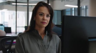 Şirket ofisindeki masada bilgisayar kullanan beyaz gömlekli genç bir kadın.