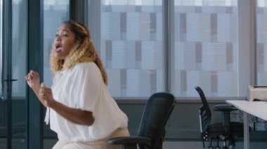 İş kıyafetleri içinde dans eden ve ofiste kutlama yapan bir grup mutlu çok ırklı iş arkadaşı.