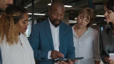 Ofisteyken dijital tablet kullanarak konuşan çok ırklı iş adamları grubu