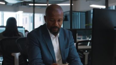 İş hayatında odaklanmış siyahi bir adam şirket ofisindeki bilgisayarda çalışıyor.