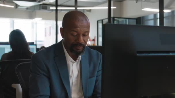 Dojrzały Czarny Mężczyzna Ubraniu Biznesowym Uśmiechnięty Podczas Pracy Komputerze Biurze — Wideo stockowe
