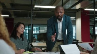 İş hayatında çalışan çok ırklı bir grup şirket toplantısı sırasında dijital tablet etrafında konuşuyorlar.