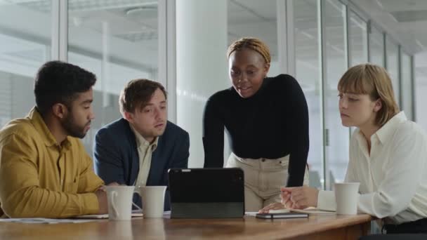 企業のオフィスで会議でデジタルタブレットの周りで話している4人の若い多文化ビジネスの人々 — ストック動画