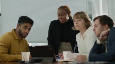 Şirket ofisindeki toplantı sırasında dijital tablet kullanarak video görüşmesi yapan dört çok ırklı iş adamı.