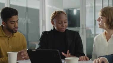 İş kıyafetleri giyen dört genç şirket ofisinde konuşurken dijital tablet kullanıyor.