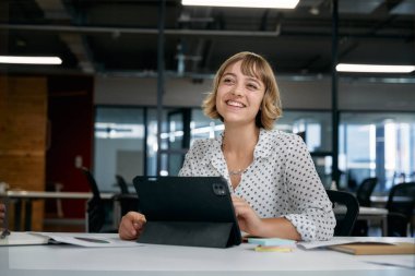 Şirket ofisindeki toplantı sırasında dijital tablet kullanırken gülümseyen iki çok ırklı iş adamı