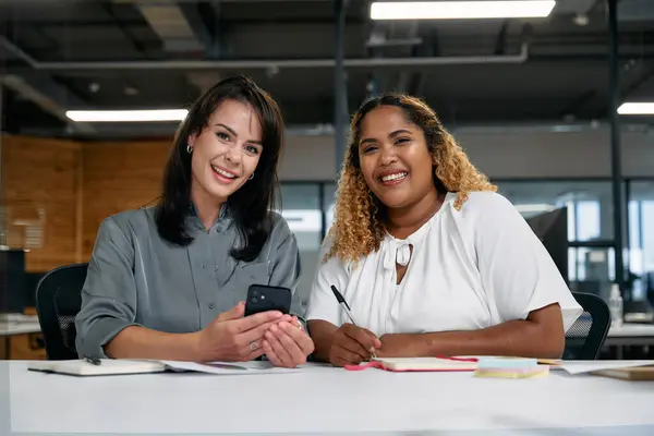 Två Multiraciala Affärskvinnor Ler När Använder Smarttelefon Mötet Företagets Kontor — Stockfoto