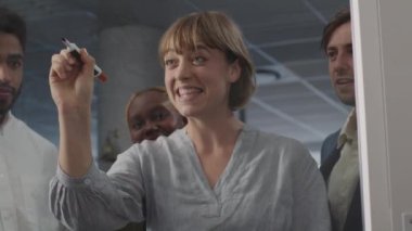 Şirket ofisindeki toplantı sırasında yazıp konuşan dört mutlu çok ırklı iş adamı.